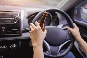begrepp av körning berusade, hand innehav alkohol medan körning. foto