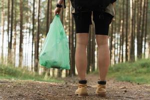 kvinna vandrare samlar plast avfall i grön skog foto