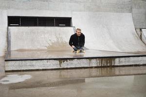 motiverad handikappade kille med en longboard i de skatepark foto