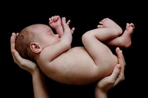 söt nyfödd bebis liggande i de mors händer foto