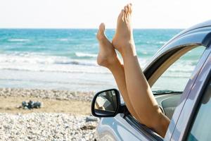 kvinna ben dinglande från bil fönster mot hav foto