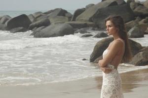 ung kvinna bär skön vit klänning är Framställ på de strand foto