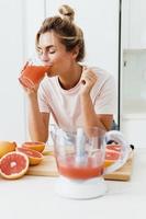 kvinna dricka nyligen pressas hemlagad grapefrukt juice i vit kök foto