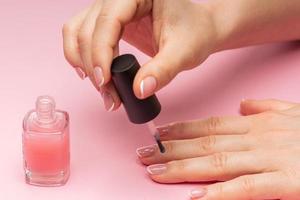 kvinna hand med skön franska manikyr applicering rosa nagel putsa foto
