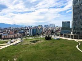 grön parkera i en modern stor stad, megalopolis med hög glas hus, byggnader, skyskrapor mot de blå himmel av de bergen på en tropisk värma sommar tillflykt, resten foto