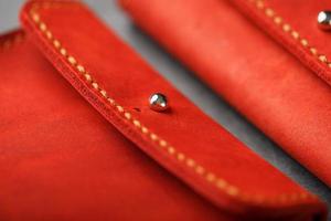 handväska tillverkad av äkta röd läder, handgjort på en mörk bakgrund. sys sömmar. foto