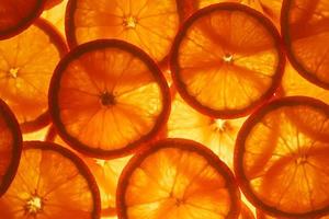 skivor av massa och krydda mogen orange med bakgrundsbelysning som en textural bakgrund, de substrat. full skärm, närbild foto