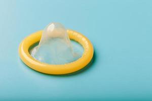 öppnad kondom på en blå bakgrund. använda sig av av skydd till minska de sannolikhet av sexuellt överförs sjukdomar eller graviditet. foto