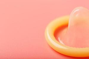 öppnad kondom på en rosa bakgrund, närbild, topp se. foto