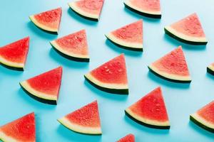 mönster av skivor av färsk skivor av röd och gul vattenmelon på en blå bakgrund. topp se foto