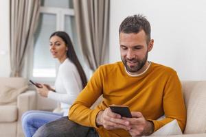 fru vände sig henne tillbaka till Make, läsning meddelande på telefon från henne älskare, man spelar spel på mobil telefon. fusk och otrohet begrepp foto