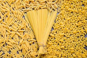 rå pasta olika typer av okokt pasta makaroner spaghetti och spaghetti på bakgrund - topp se, italiensk mat kulinariska begrepp, samling av annorlunda rå pasta på matlagning tabell för matlagning mat foto