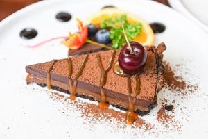 chokladkaka karamell med körsbär och frukt på vit platta - närbild kaka skiva foto