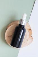 kosmetisk flaska med pipett på trä- skiva topp se, platt lägga på färgad bakgrund. naturlig kosmetisk begrepp foto
