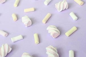 färgrik marshmallow lagd ut på violett papper bakgrund. pastell kreativ texturerad mönster. perspektiv makro skott foto