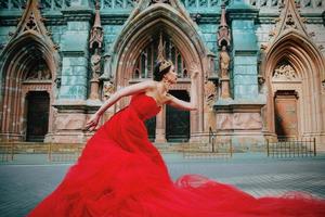 skön kvinna i lång röd klänning och i kunglig krona nästan katolik katedral foto