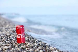 antalya, Kalkon - Maj 18, 2022 original- coca cola röd tenn kan lögner på små runda sten stenar stänga till hav Strand. Coca Cola på turkiska strand foto