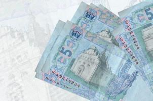 5 ukrainska hryvnias räkningar lögner i stack på bakgrund av stor halvtransparent sedel. abstrakt presentation av nationell valuta foto