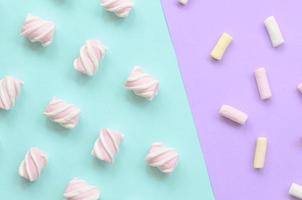 färgrik marshmallow lagd ut på violett och blå papper bakgrund. pastell kreativ texturerad mönster. minimal foto