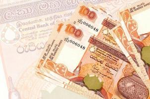 100 sri lankanska rupier räkningar lögner i stack på bakgrund av stor halvtransparent sedel. abstrakt presentation av nationell valuta foto