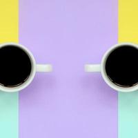 två små vit kaffe koppar på textur bakgrund av mode pastell blå, gul, violett och rosa färger papper i minimal begrepp foto