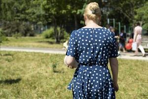 polka punkt klänning. kvinna i parkera. flicka promenader ner gata. foto