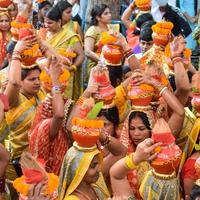 New Delhi, Indien 3 april 2022 - kvinnor med kalash på huvudet under jagannath-templet mangal kalash yatra, indiska hinduistiska hängivna bär jordkrukor som innehåller heligt vatten med en kokosnöt på toppen foto