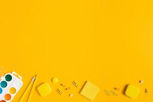 gul bakgrund med vattenfärg och pennor för skola reklam. foto