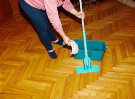 mopp din trä golv. en kvinna förbereder en mopp. hushållning begrepp. foto