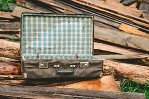 gammal tömma resväska på trä- pinnar, mot de bakgrund av en bruten hus foto