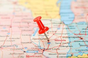 röd prästerlig nål på en Karta av usa, Illinois och de huvudstad springfield. stänga upp Karta av Illinois med röd kryssa foto