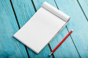 anteckningsblock med röd penna på en blå trä- tabell bakgrund, för utbildning, skriva mål och gärningar foto