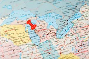röd prästerlig nål på en Karta av usa, Michigan och de huvudstad lansing. stänga upp Karta av Michigan med röd kryssa foto