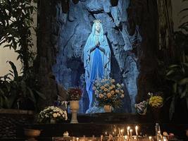 de grotta av jungfrulig Mary, staty av jungfrulig mary i en sten grotta kapell katolik kyrka med tropisk vegetation foto