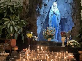 de grotta av jungfrulig Mary, staty av jungfrulig mary i en sten grotta kapell katolik kyrka med tropisk vegetation foto