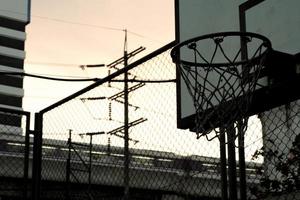 hög vinkel se av gammal basketboll ring med rörelse suddig tåg i de skymning himmel bakgrund foto