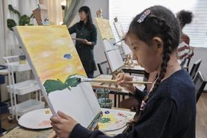 en liten flicka koncentrat på akryl Färg bild målning på duk med studerande barn i ett konst klassrum, kreativ inlärning med talanger och Kompetens i de elementärt skola studio utbildning. foto