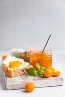 skivad hantverkare hemlagad bröd med ricotta eller stuga ost och orange sylt på ljus bakgrund. gott frukost. hög nyckel fotografi. foto