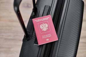 ryska pass på en svart resa resväska, topp se, selektiv bakgrund. emigration av ryssar, sökande asyl foto