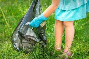 barn plockar plast skräp från gräs foto