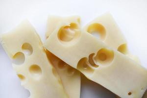 bitar av gul ost med stor hål på en vit bakgrund. utsökt ost närbild. foto