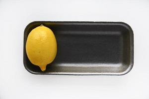 mogen gul citroner på en svart plast stöd. utsökt citroner från de Lagra på en vit bakgrund. gul citroner packade i en behållare. foto