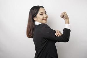 upphetsad asiatisk företag kvinna bär en svart kostym som visar stark gest förbi lyft henne vapen och muskler leende stolt foto