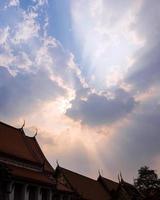 solstråle bakom solnedgångsmolnen över det buddhistiska templet foto