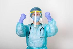 läkare, sjuksköterska bär skydd kostym för stridande covid-19 coronavirus med vit bakgrund. medicinsk arbetstagare i skyddande kostym med ansikte skydda innehav henne nävar upp till bekämpa coronavirus utbrott foto