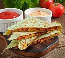 mexikansk quesadilla skivad med grönsaker och såser på bordet foto