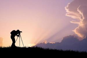 en professionell fotografs siluett är fokuserad på att fotografera på en vacker äng. foto