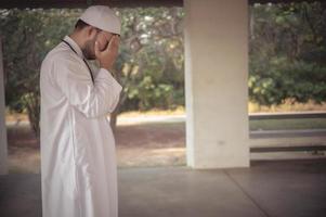 ung asiatisk muslim man bön- på solnedgång, ramadan festival begrepp foto