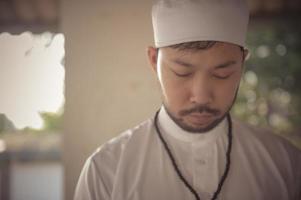 ung asiatisk muslim man bön- på solnedgång, ramadan festival begrepp foto