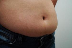 asiatisk kvinna visar fet mage stor storlek övervikt och fetma på kontoret. foto